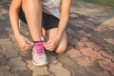 Woman Lacing Up Her Gray and Pink Nike Low-top Athletic Shoe