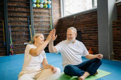 An Elderly Couple High Fiving each other while Sitting in the Gym