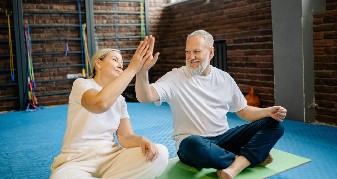 An Elderly Couple High Fiving each other while Sitting in the Gym