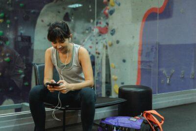 Young woman using smartphone while resting after training in gym